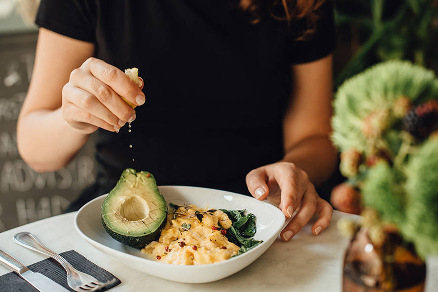 Woman eating scrambled eggs and avocado